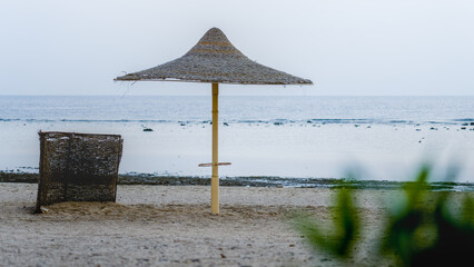 A single sun umbrella and windbreak stand quietly on the beach of an Egyptian resort in the early morning light.
