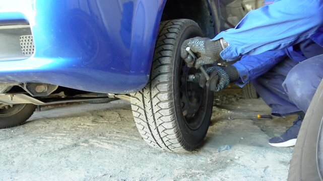 Bila Tserkva, Ukraine, April 27, 2025: A mechanic loosens the lug nuts of a car wheel during a tire repair or replacement