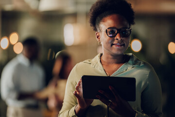 Black businesswoman using digital tablet in office at night