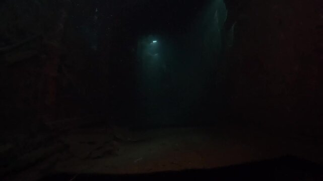 a diver swims through WWII ship wreck underwater in Coron island, Philippines