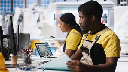 Black employee manages solar panel configuration via desktop tools, optimizing factory output and troubleshooting. Technician updates energy system parameters on pc. Camera A.