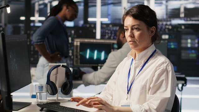 Data center software developer using PC to monitor neural network AI visualization. Woman working in server room using computer to oversee rigs powering machine learning processes, camera A