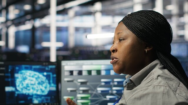 Data center engineering team deploying AI solutions optimizing gear. Server hub teamworking colleagues working together, using artificial intelligence to minimize systems downtime, camera B