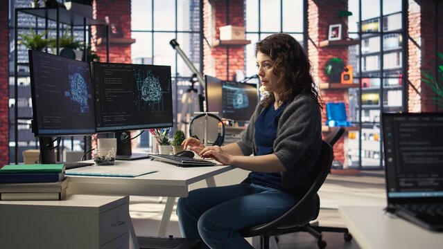 IT technician writing code and debugging on artificial intelligence neural networks computerized brain model. Female tech support doing checkup on AI systems, cloud computing. Camera A.