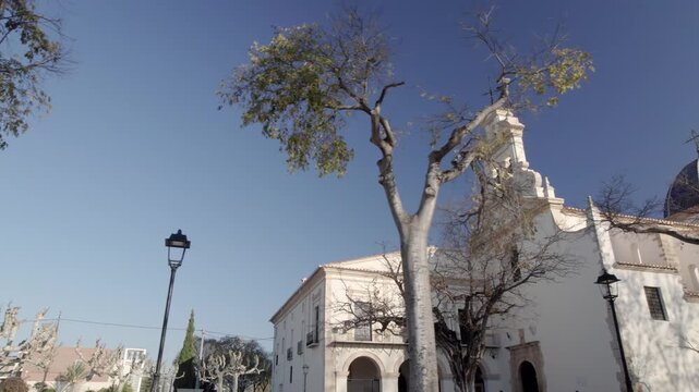Side view of the beautiful Basilica de Lledo under the trees with a cloudless blue sky in the background, Castello, Valencia, Spain