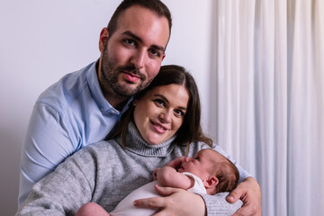 Young parents happily embracing their newborn baby