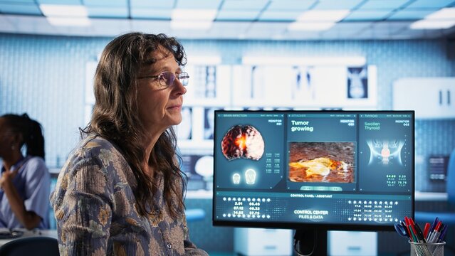 Male physician does fever measurements with a digital thermometer, consulting senior female patient at the cabinet. Old specialist checking temperature for disease prevention. Camera A. - Powered by Adobe