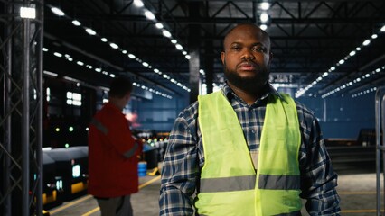 African american plant engineer standing near steel machinery during construction tasks, showcasing production responsibility and the power of fabrication. Hi vis vest for safety.