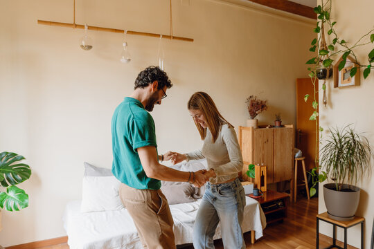 A woman and a man are dancing and holding hands while smiling and looking down