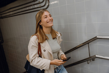 Woman smiling and looking ahead while walking and holding phone