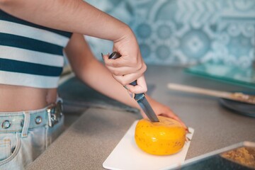 Home cook girl cuts traditional Dutch cheese, helps prepare breakfast