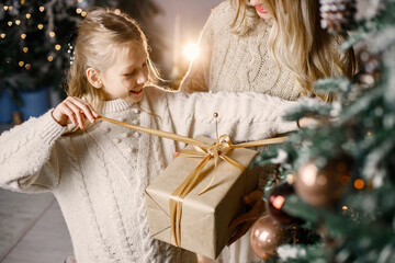 Cropped photo of a little girl standing near christmas tree at home with her mother