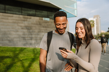 Male and female athletes laughing and standing while looking at the phone she is showing