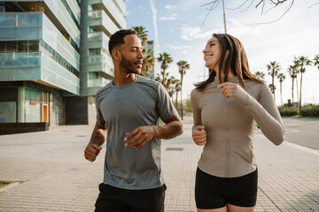 A male athlete talks to a female athlete who laughs as they run side by side