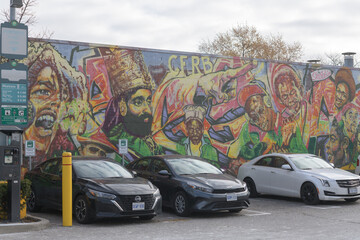 Fototapeta premium Green P, a parking lot, (Municipal Carpark 667), located at 1531 Eglinton Av W, with cars and Reggae Lane Mural by artist Adrian Hayles, Little Jamaica, Toronto