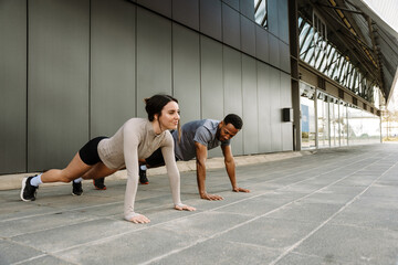 Fototapeta premium Female and male athletes are standing in push-up position and she is smiling