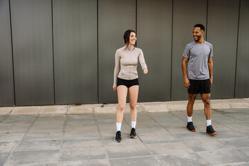 Female and male athletes laughing and talking while standing next to each other and he looking at her