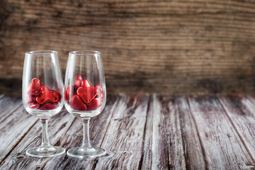 Two glasses filled with red heart candy on a rustic wooden table