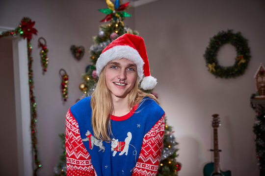 Man wearing Santa hat and festive cat sweater celebrates Christmas with holiday decorations