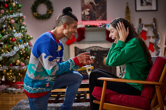 Man proposes to surprised woman with engagement ring during festive Christmas celebration at home