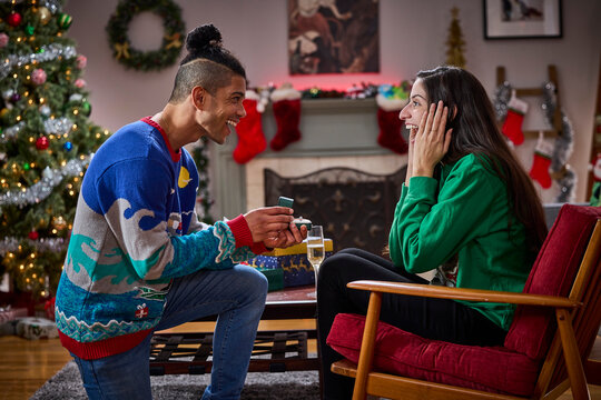 Man proposes to surprised woman with engagement ring during festive Christmas celebration at home