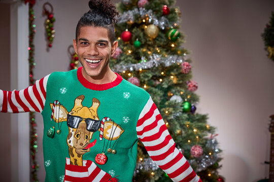 Man wearing festive green ugly Christmas sweater with giraffe design and candy cane striped sleeves - Powered by Adobe