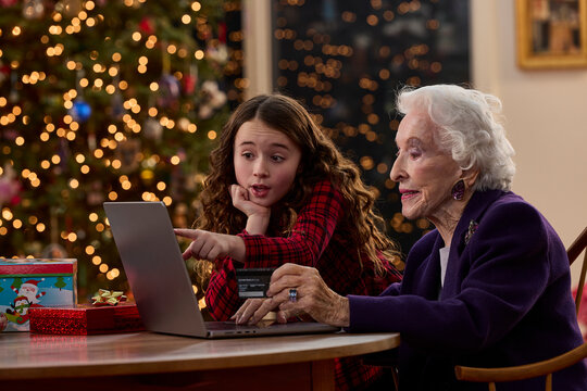 Grandmother and granddaughter shopping online together with laptop during Christmas holiday season at home