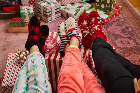 Cozy holiday vibes with festive socks and pajamas by the christmas tree and presents