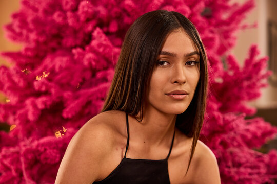 Woman in black halter top poses against vibrant pink bougainvillea flower backdrop