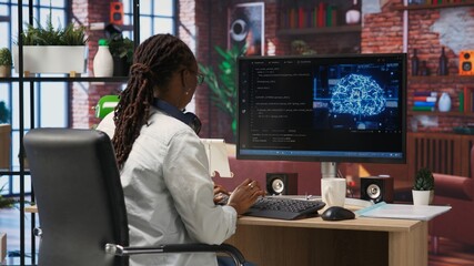 Admin uses computer for artificial intelligence computing simulation, waiting for code to finish compiling. African american woman works with AI deep neural networks at home, camera B