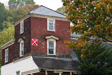 Abandoned red house marked unsafe with emergency x sign on an autumn day in the Brighton area of Boston, Massachusetts, USA
