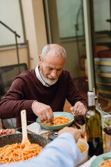 Man holding hand over plate of food while sitting at table