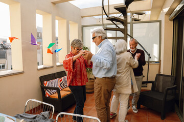 A group of four friends dance between chairs and hold hands while three of them smile