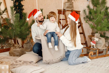 Mother, father near their son sitting on a swing on Christmas eve