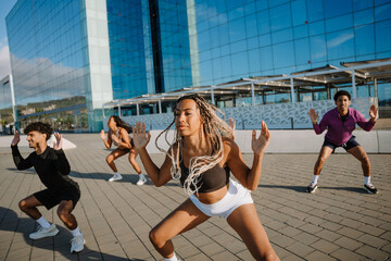 A group of five athletes squatting and holding their arms out to the sides and up