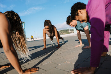 A group of four athletes stand in a semicircle in a push-up position
