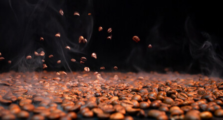 Coffee beans are falling and releasing steam in a dark background