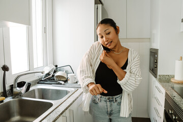 A woman walks and talks on a phone that she holds with her shoulder and hand