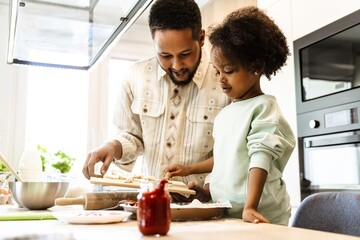 A daughter picks mushrooms from a board held by her father, who is talking while they stand at the table