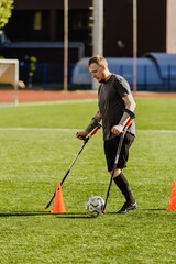 Obraz premium Man on crutches walking towards ball near cone