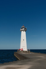 Low angle image of the concrete and stone pier leading to the Sodus Point Lighthouse on Lake Ontario in New York State on a beautiful afternoon