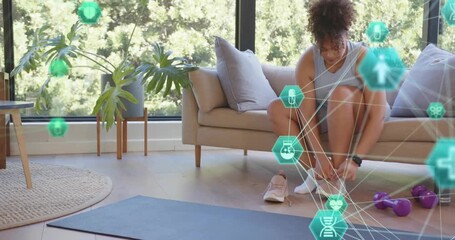 Woman preparing workout on sofa reaching for sneaker, tying laces while fitness overlay appearing - Powered by Adobe