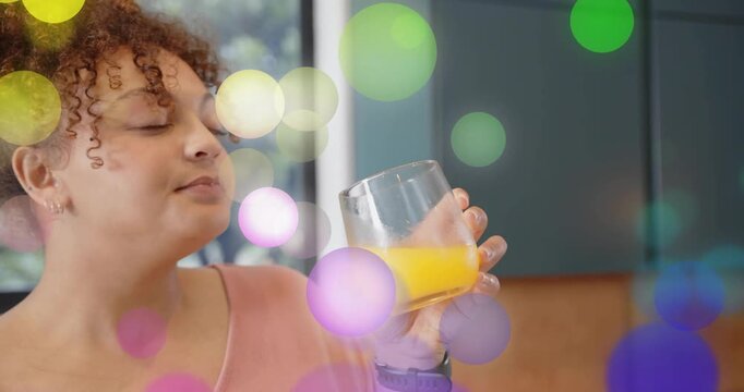Woman lifting OJ glass in kitchen, smelling, tilting, sipping for taste test, overlays hiding face