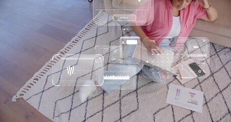 Woman sitting on rug typing on laptop, holo UI panels appearing above while analyzing tech data - Powered by Adobe