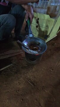 Cinematic vertical footage of a vendor grilling kerak telor at night. Videography of street food being prepared by the vendor in 4K resolution footage.