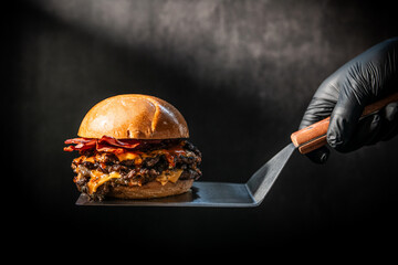 Gourmet Double Smash Burger with Crispy Bacon and Melted Cheese on a Spatula