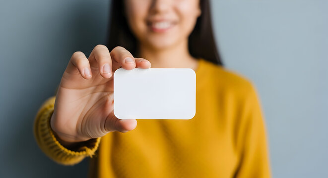 Showcasing a blank business card, a young professional woman smiles, presenting the card in a bright, modern office space, ready for your message.