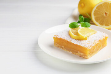 Tasty lemon bar with powdered sugar and mint on white wooden table, closeup. Space for text