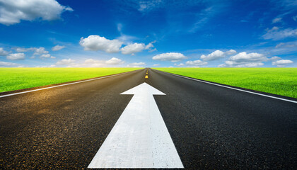 Empty asphalt road with a white arrow sign pointing forward to the horizon, symbolizing a path to future success and growth