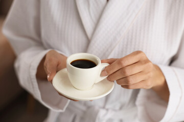 Woman in bathrobe with morning coffee indoors, closeup